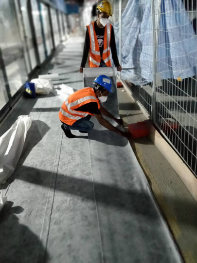 Workers laying touch-voltage membrane on a walkway